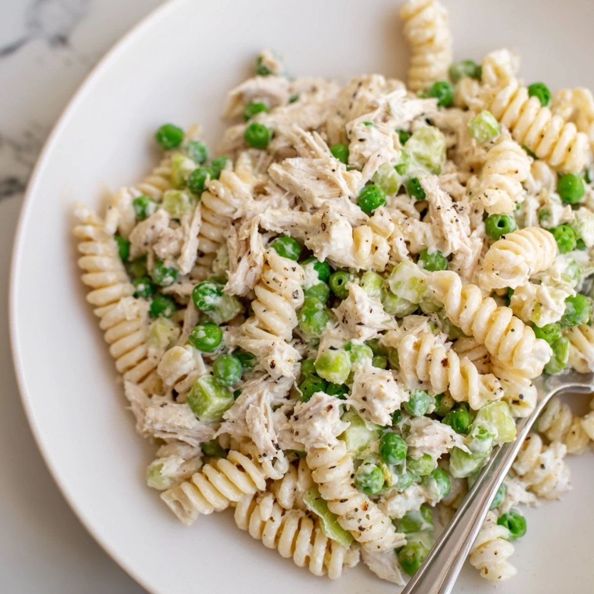 Creamy tuna pasta salad served chilled with vibrant peas and crunchy celery.  