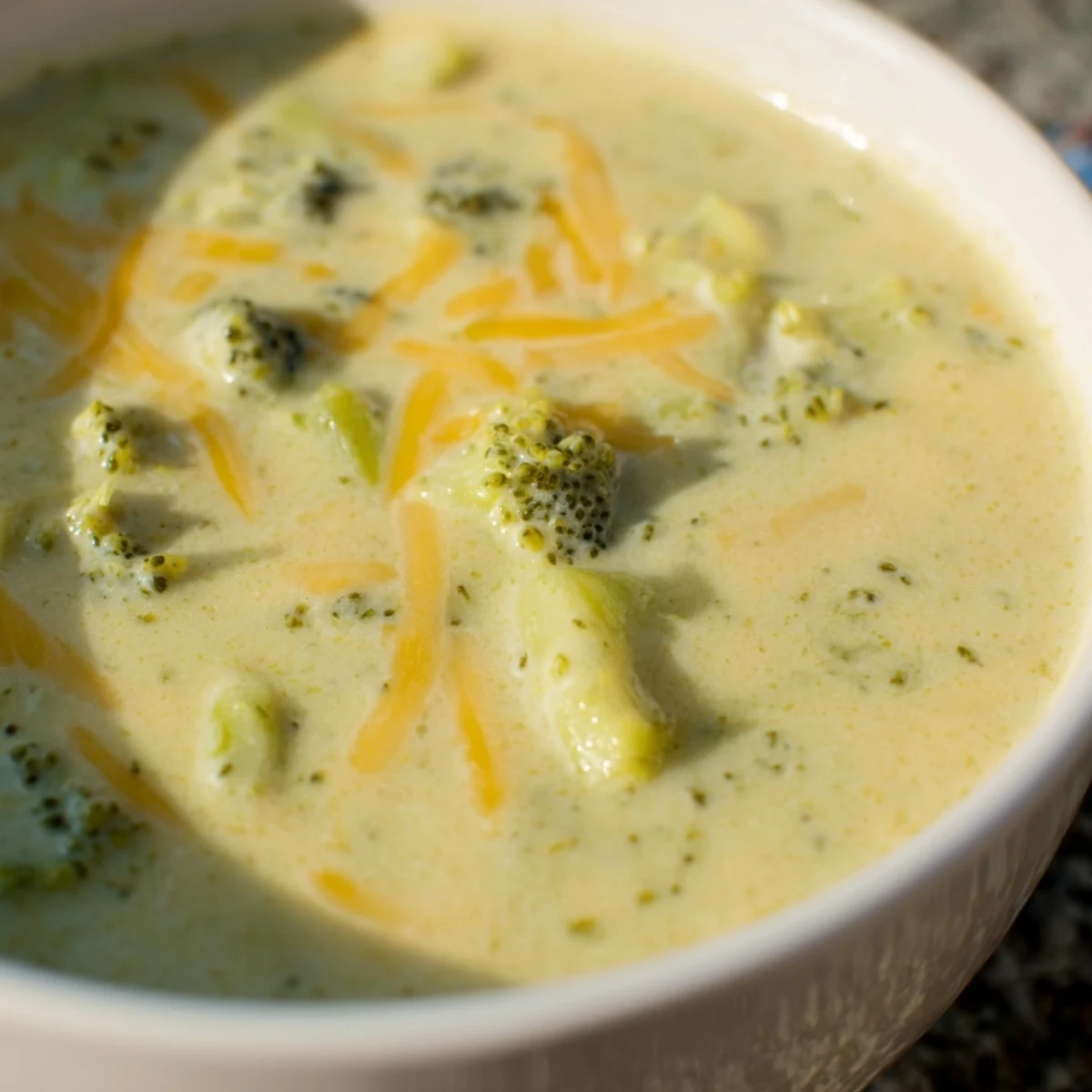 Steaming bowl of Broccoli Cheese Soup with melted cheddar, perfect for a cold evening.