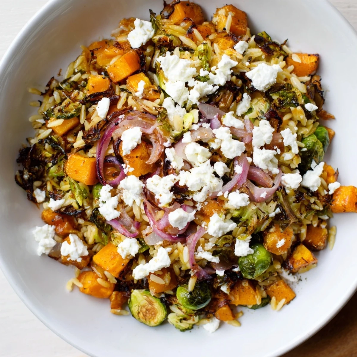 A colorful bowl of Best Fall Harvest Orzo Salad, tossed together with maple vinaigrette and fresh veggies.