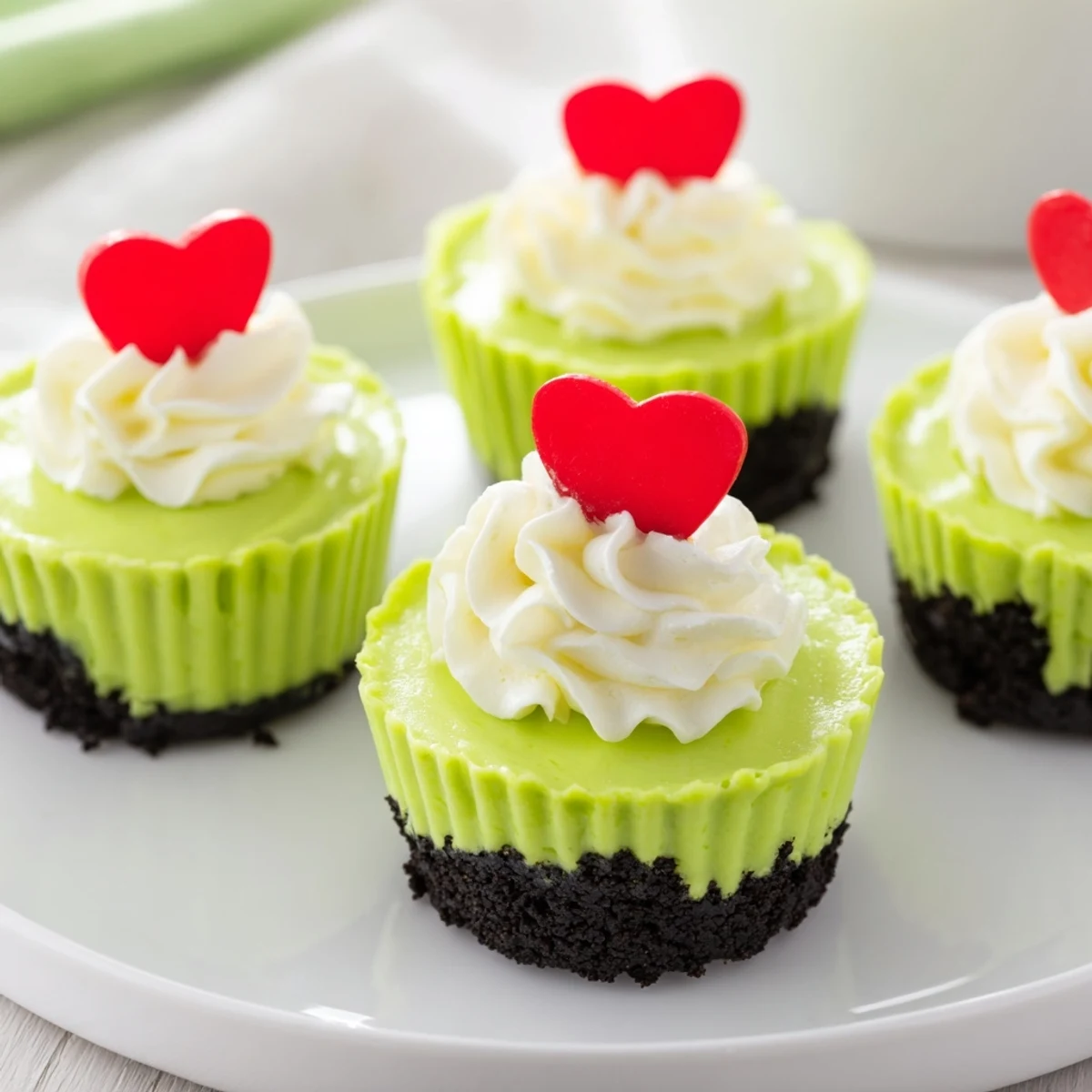 Bright green, cheerful Grinch mini cheesecakes, arranged on a serving plate ready to be devoured at your holiday party.