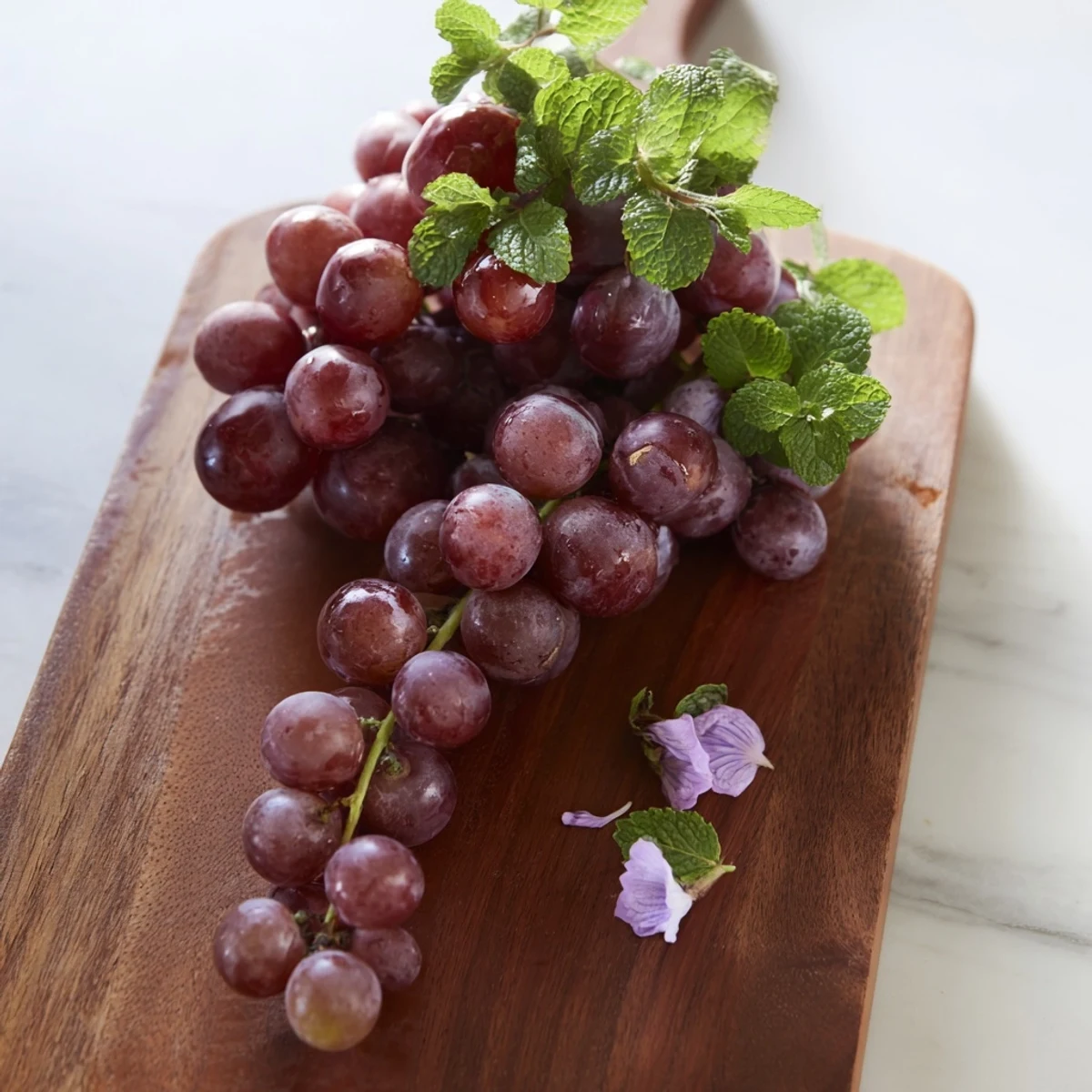 Freshly washed grapes cluster, spilling beautifully over the board's edge for a colorful summer snack.