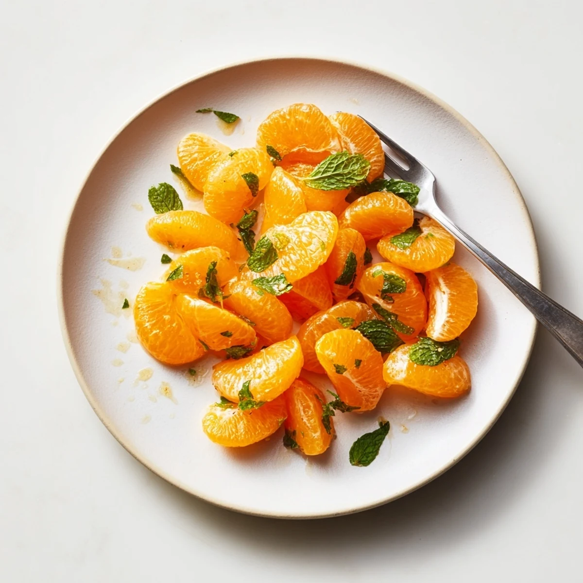 A bright bowl of winter fruit salad: clementines, mint, and lime, a perfect refreshing dessert.