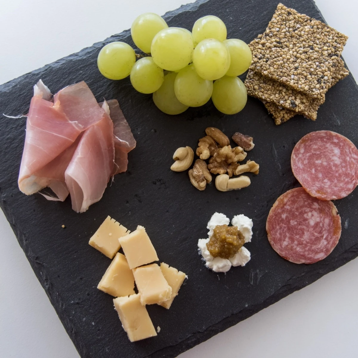 A beautifully arranged Charcuterie Board for One, offering delicious meats, cheeses, and grapes to enjoy.