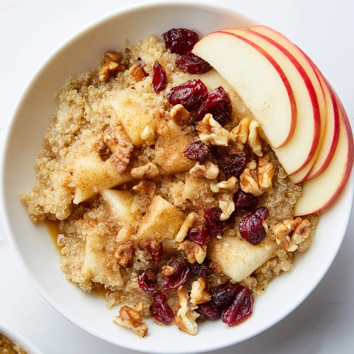 Golden-hued Apple Cinnamon Quinoa Bowl, with apple slices and a drizzle of maple syrup adding sweetness.