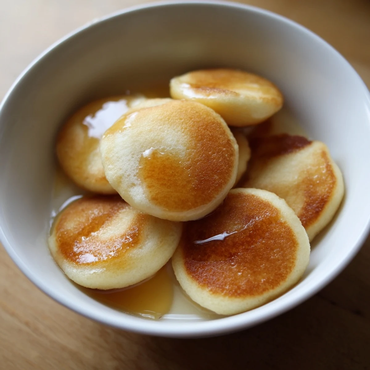 Fluffy Pancake Cereal: Golden-brown mini pancakes piled in a bowl, ready for syrup and milk.