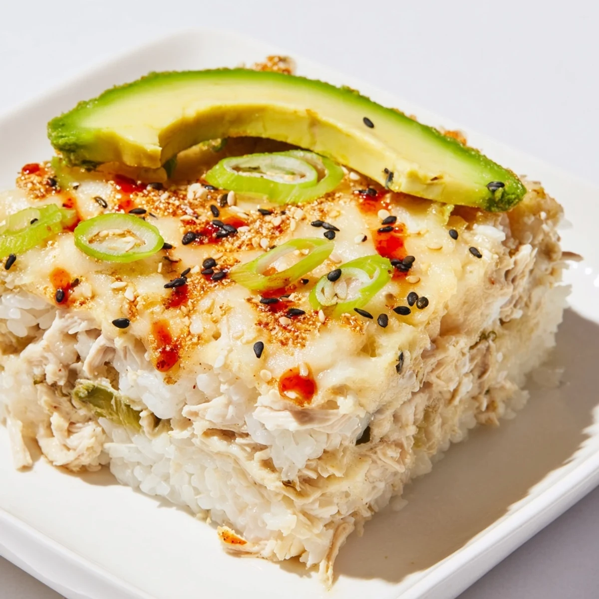 Golden-brown Chicken Sushi Bake with melted cheese, avocado slices, and crispy nori sheets.