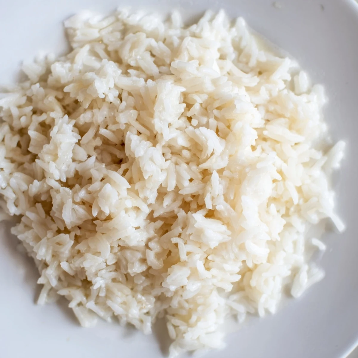 Steaming bowl of Coconut Jasmine Rice, fluffy and fragrant, ready to serve with a Thai curry.