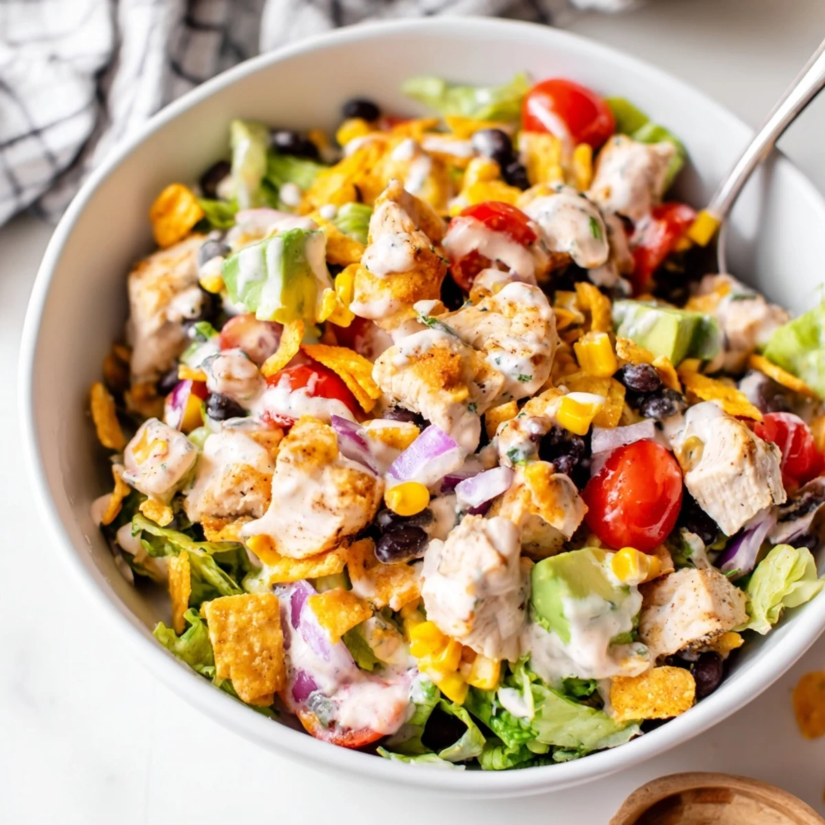 A hearty bowl of Chicken Taco Chopped Salad with seasoned chicken, crisp lettuce, avocado, and crushed tortilla chips, topped with creamy salsa ranch dressing.