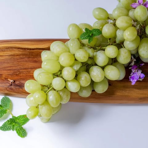 Juicy red and green grapes cascade over the serving board, a fresh appetizer ready to eat.