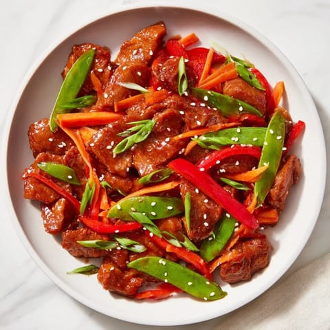 This sweet teriyaki pork stir-fry showcases tender pork and vibrant vegetables coated in a rich sauce.