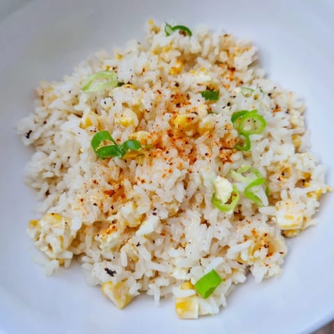 A colorful bowl of Mexican Street Corn Rice, bursting with flavor and topped with cheese and herbs.