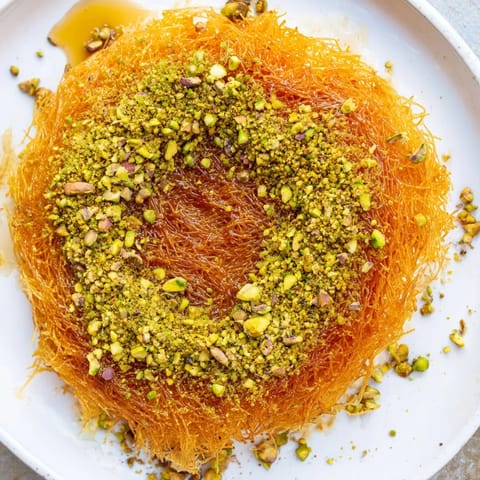 A delightful slice of Lebanese Knafeh cheese, drenched in sweet syrup and nutty toppings.