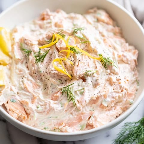 Close-up of a bowl of chilled smoked salmon dip, ready to be served with crackers and lemon wedges.