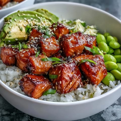 Spicy sriracha mayo drizzles over a fresh Salmon Rice Bowl garnished with sesame seeds and green onions.