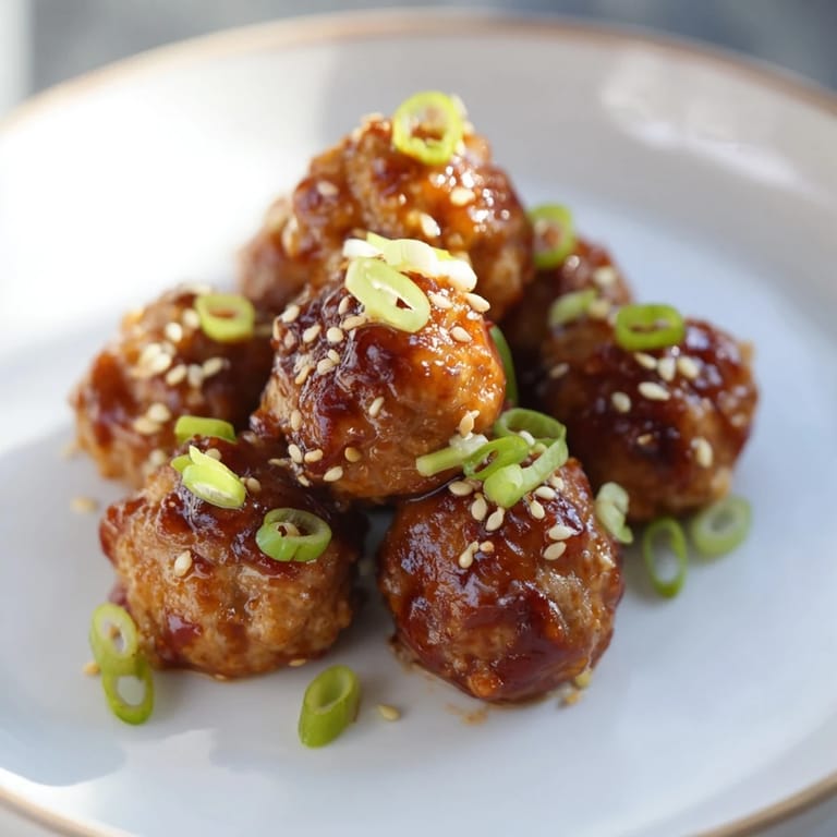 Forkful of savory Spicy Honey-Glazed Chicken Meatballs with rice, drizzled with sweet and spicy glaze.