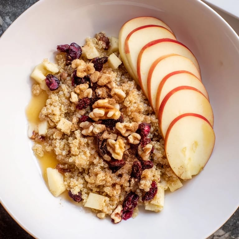Golden-hued Apple Cinnamon Quinoa Bowl, with apple slices and a drizzle of maple syrup adding sweetness.