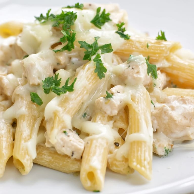 Homemade Chicken Alfredo Casserole garnished with fresh parsley, served alongside a crisp green salad for a balanced Italian-American meal.