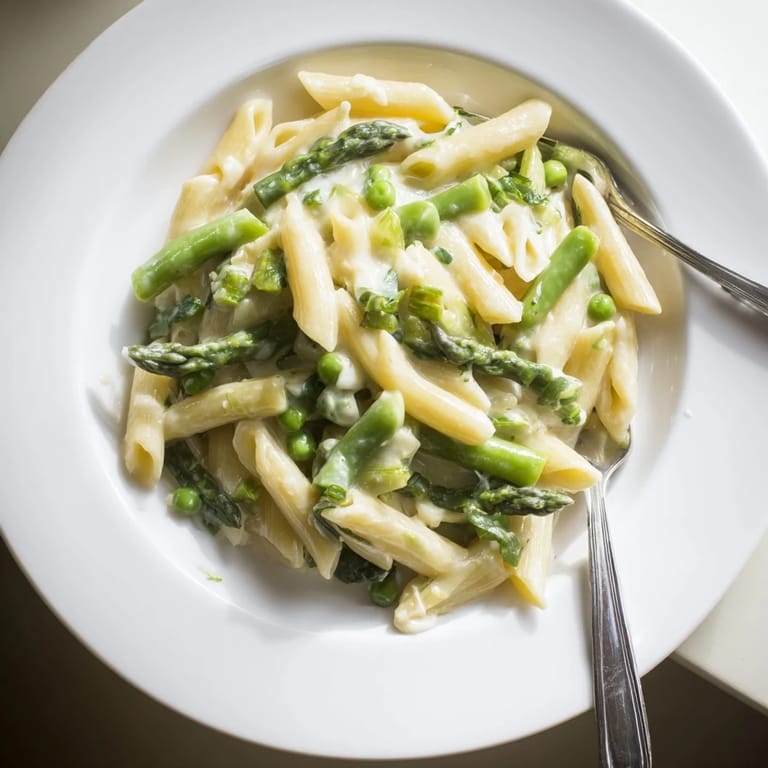 Garlic Parmesan Spring Vegetable Pasta on a white plate, featuring penne tossed with bright green vegetables and a creamy sauce, a perfect vegetarian main for spring.