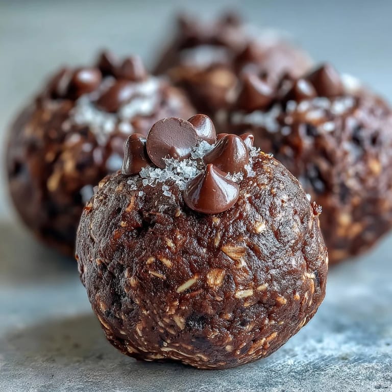 Vegan Chocolate Peanut Butter Protein Balls on a slate board with a small bowl of maple syrup, perfect for a quick post-workout snack.