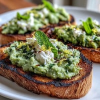 Creamy fava bean and mint topping on smoky grilled sourdough toast.